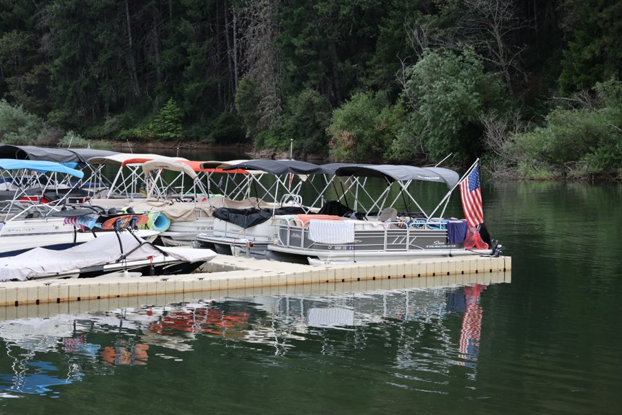 Pontoon boats at the dock with an American flag and still reflections